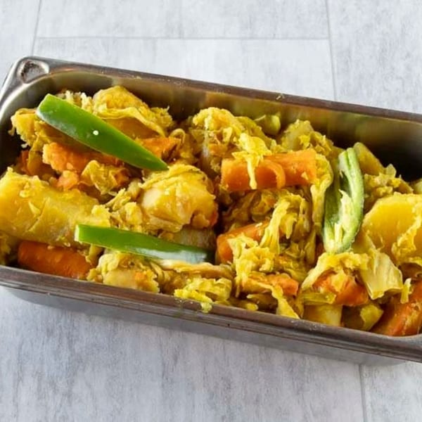 Messob Ethiopian Restaurant's yellow stew with cabbage, carrots, potatoes, and green peppers in a metal tray.