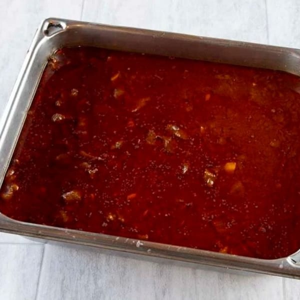 A large metal pan filled with a rich, dark red Ethiopian stew, possibly Doro Wat.