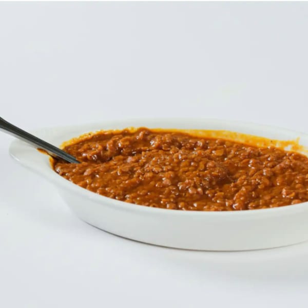 Messob Ethiopian Restaurant's red lentil stew, Misir Wot, in a white oval dish with a spoon.