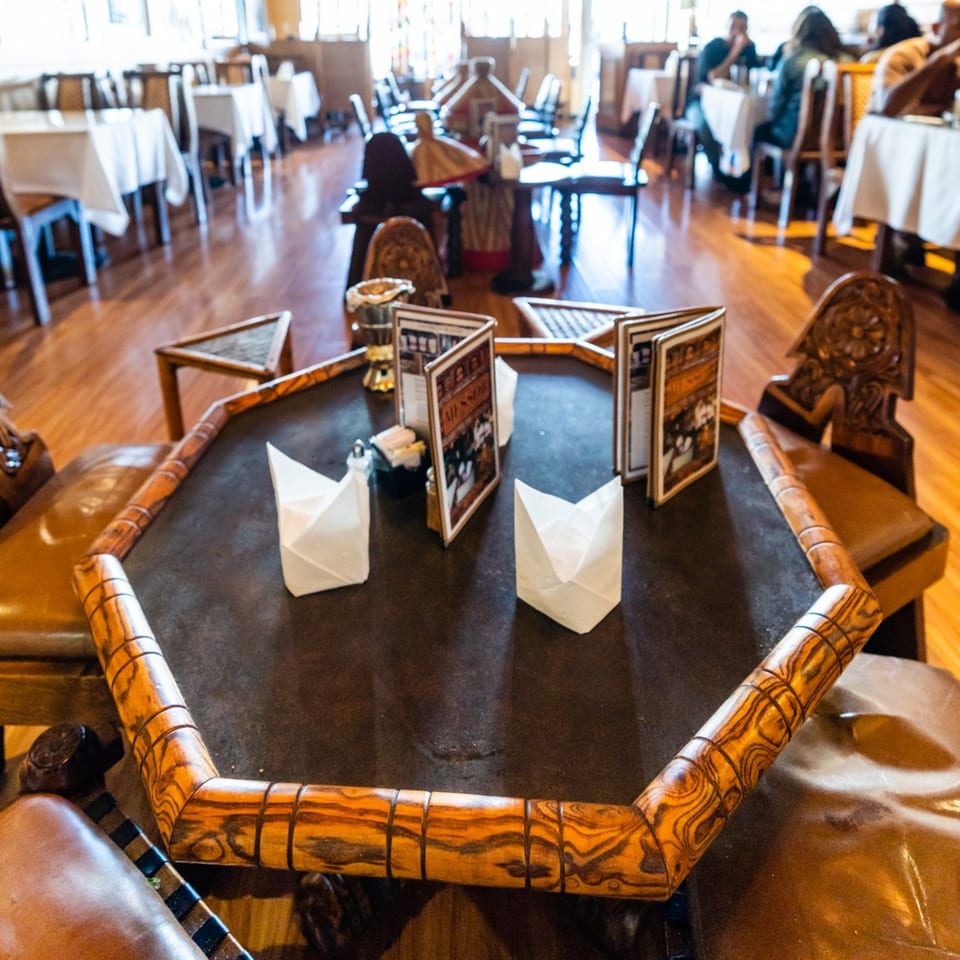 An octagonal wooden table with menus and paper lanterns, with a blurred dining room in the background.