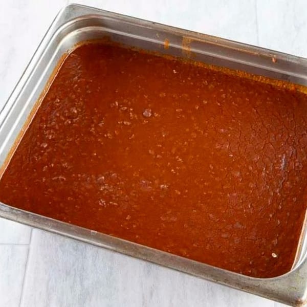 A large metal pan filled with a rich, reddish-brown Ethiopian stew, possibly doro wat.