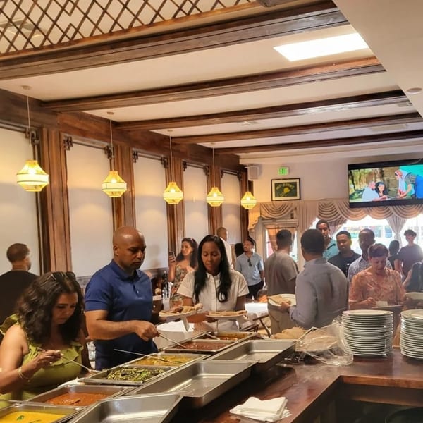 Customers at Messob Ethiopian Restaurant serving themselves from a buffet line with various dishes.